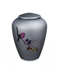 Glass cremation urn with little bird on a branch - symbol of comfort and freedom